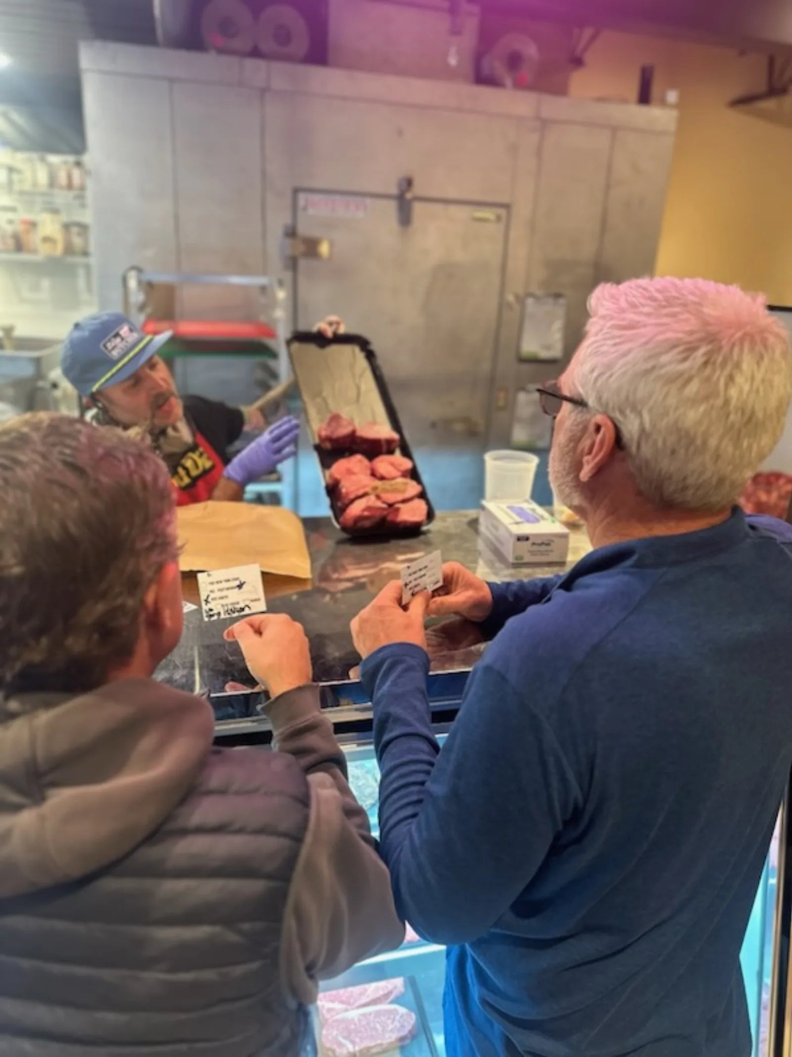 Guests picking out steaks with the butcher at the case