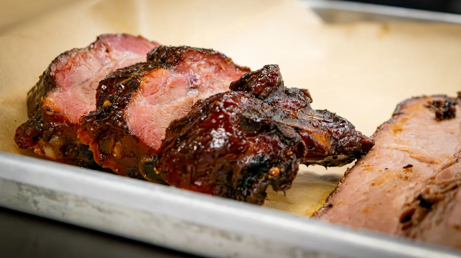 Close-up of individually sliced smoked ribs with a dark glossy glaze and visible pink smoke ring.