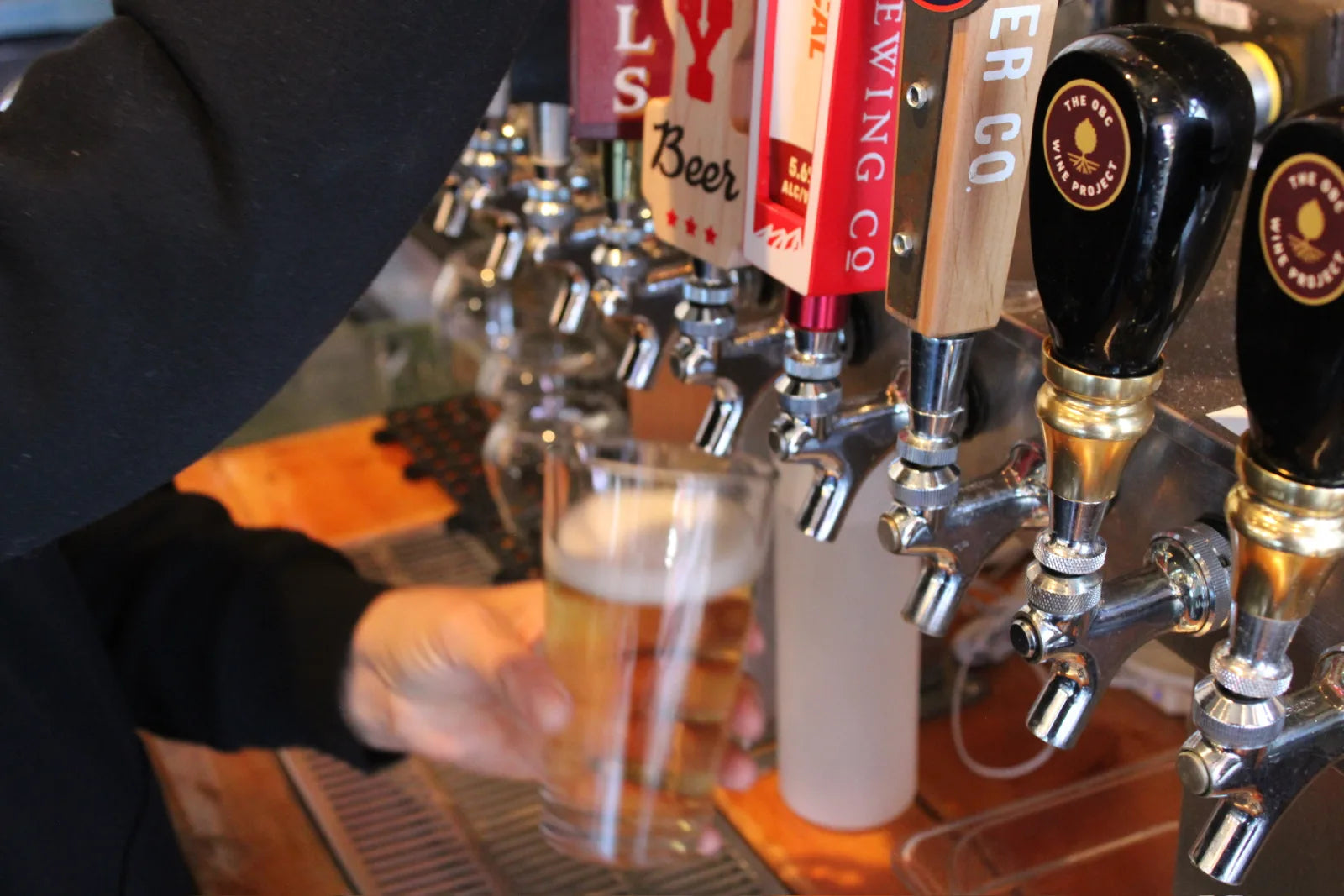 A bartender pours a draft beer into a glass beneath a row of beer and wine taps at the Cowboy Lounge bar.