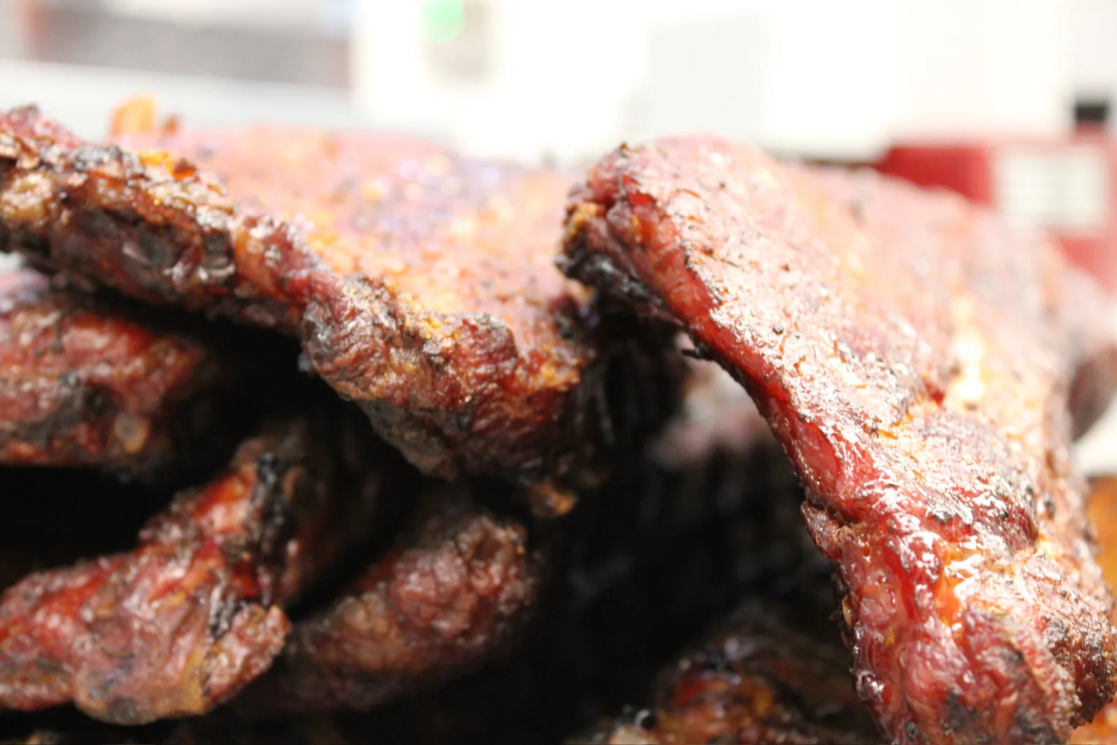 Close-up of smoked pork ribs with a deep red smoke ring and dark, peppery bark.