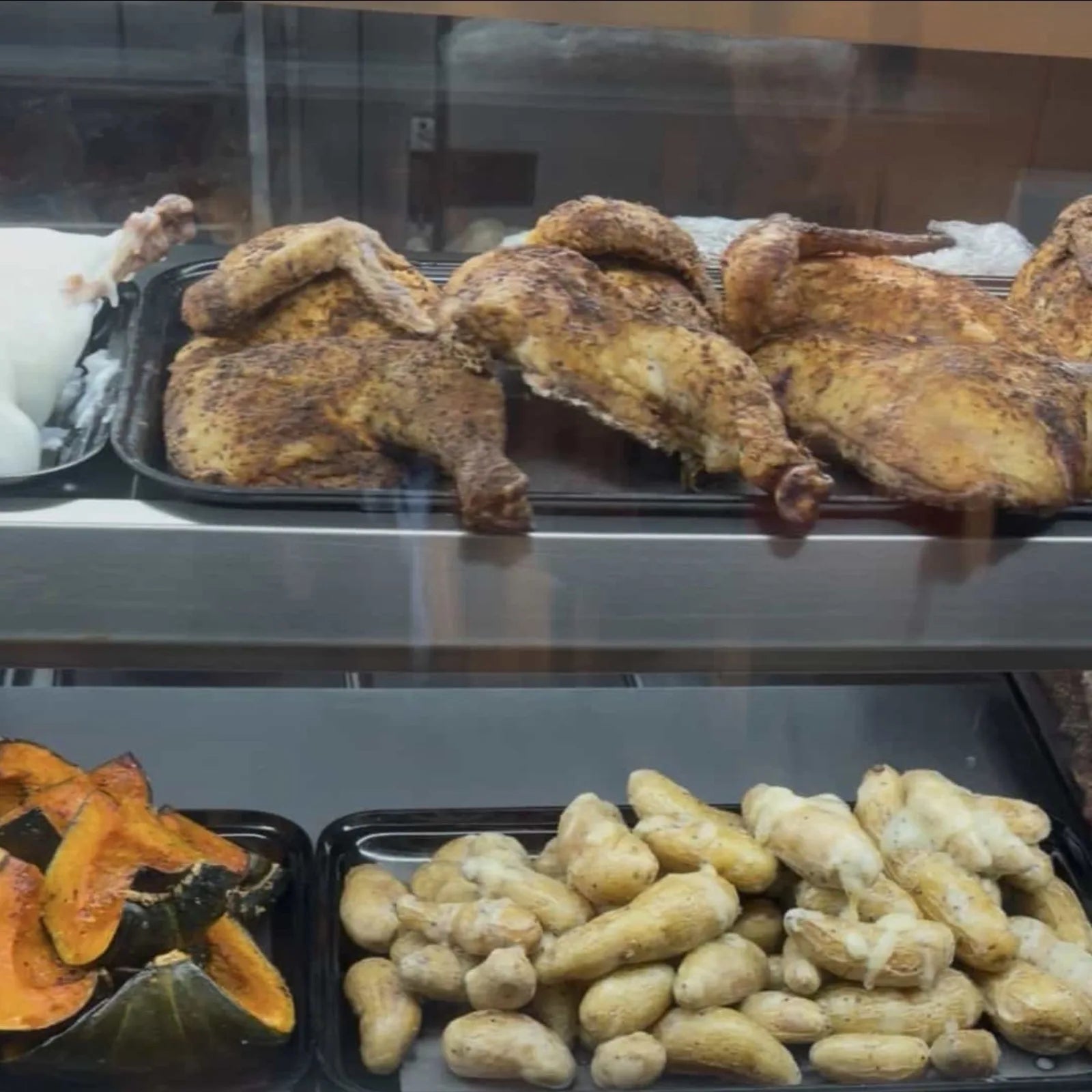 Whole roasted chickens with crisp golden skin lined up in the display case.