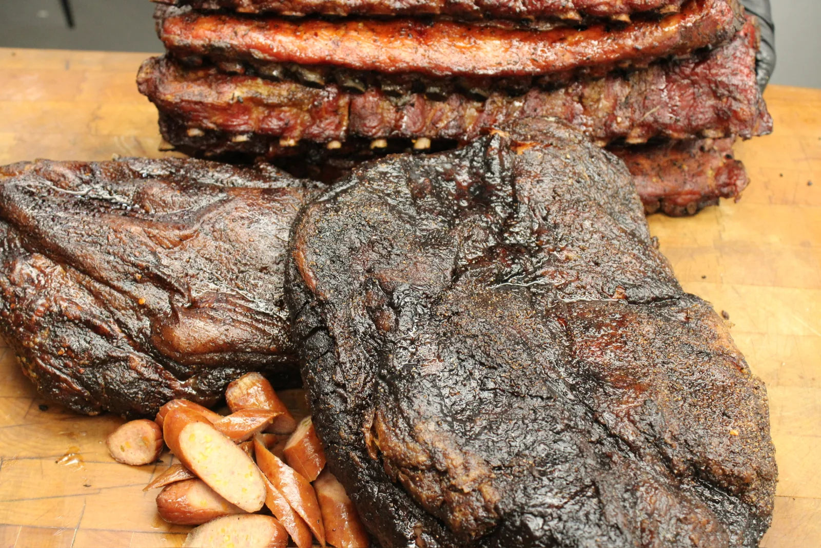 Smoked brisket and a stack of ribs on the cutting board, fresh off the smoker.