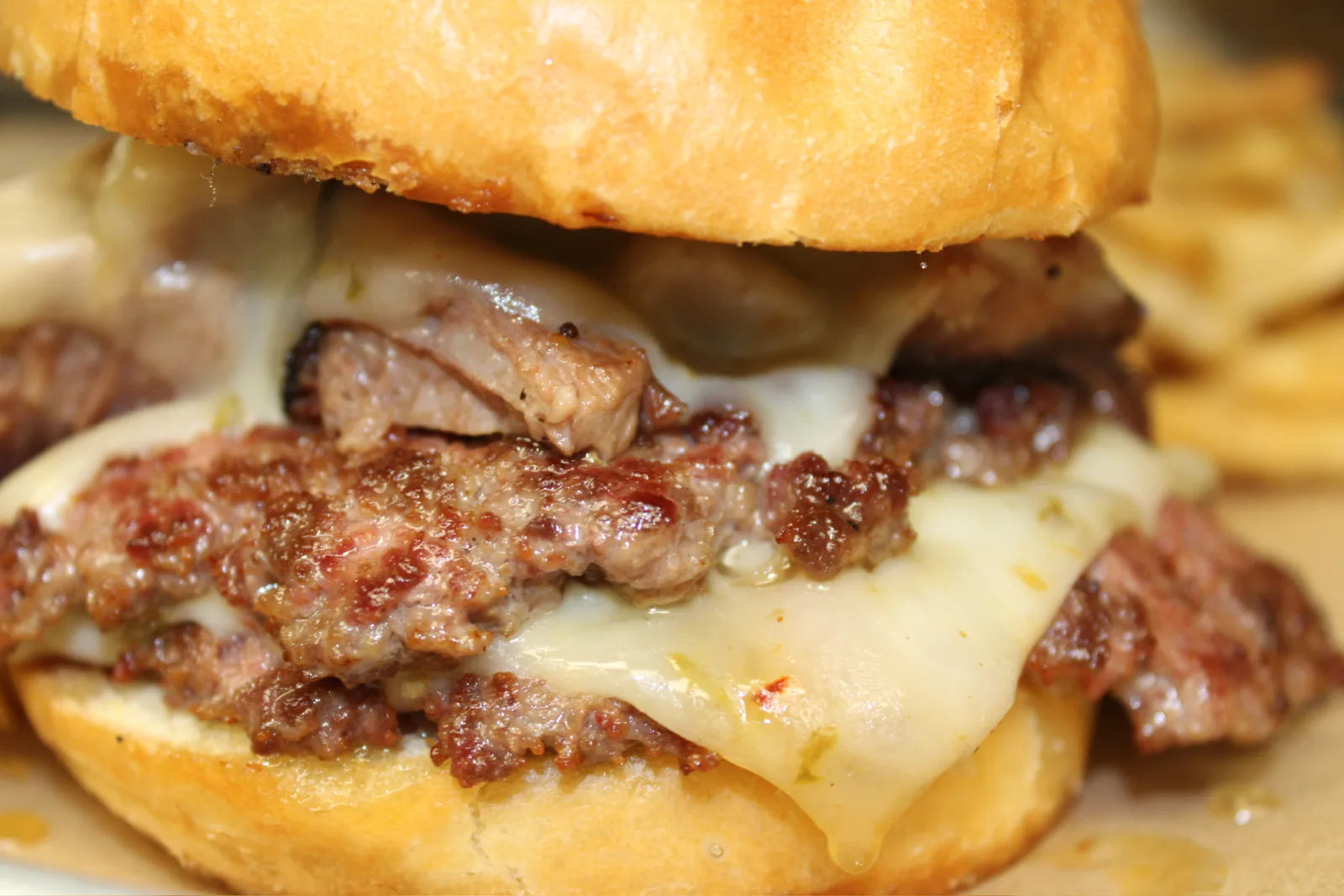 A steak melt sandwich with melted cheese, fresh off the griddle
