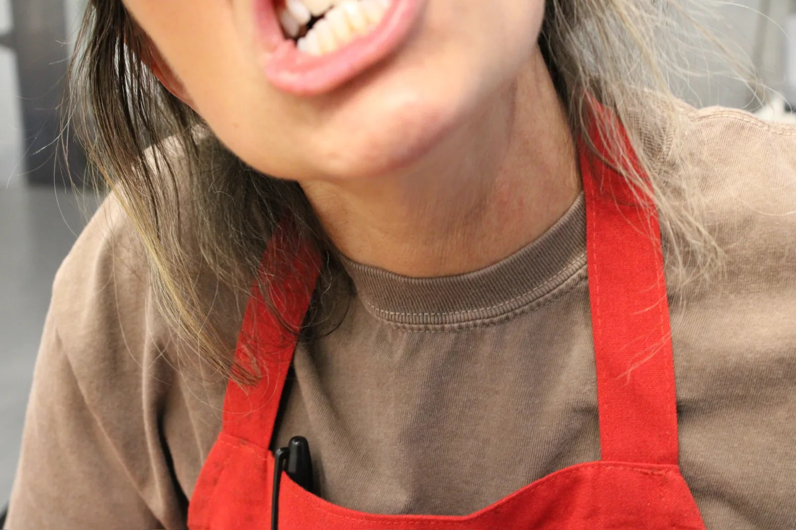 A team member in a red apron smiling in the kitchen.