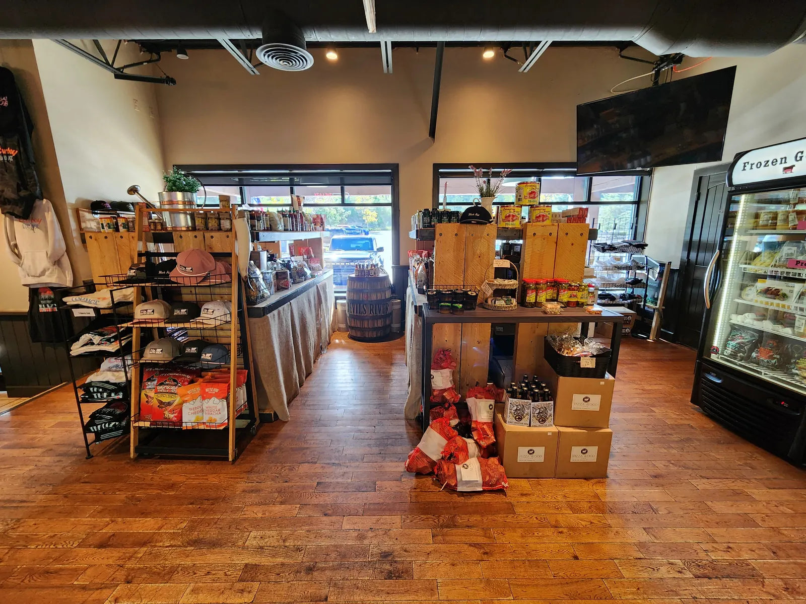 The Lazy Butcher market floor with wooden pantry displays, hats and merch racks, and a glass-door freezer case