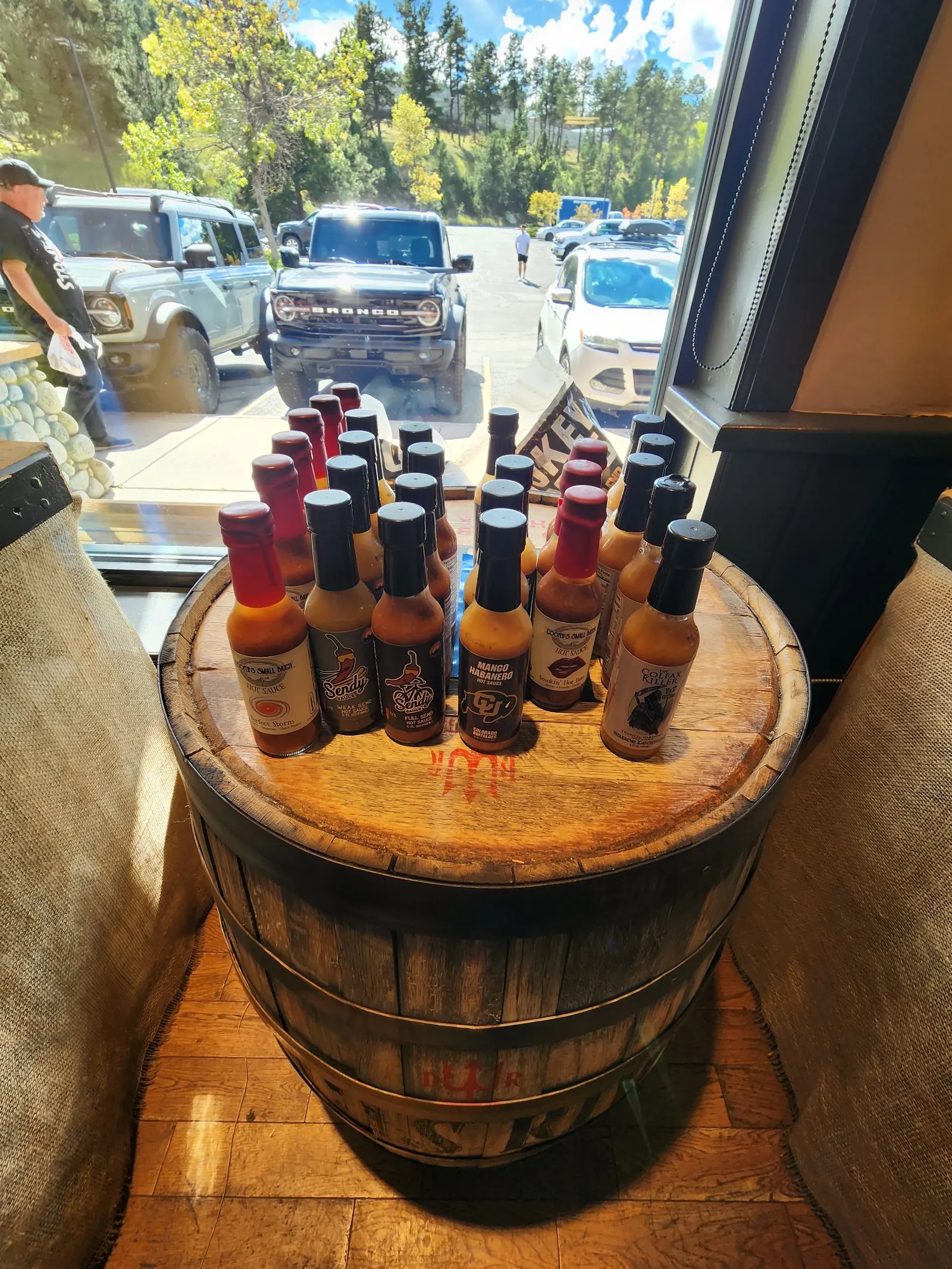 Colorado small-batch hot sauce bottles on top of a whiskey barrel by the front window